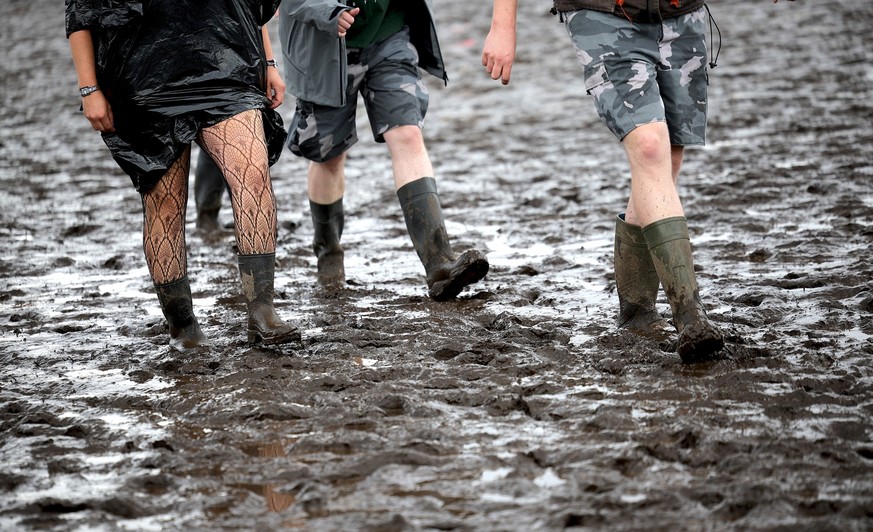 01.08.2023, Schleswig-Holstein, Wacken: Metal-Fans sind auf dem schlammigen Festivalgelände unterwegs. Das Wacken Open-Air (WOA) vom 2. bis 5. August gilt als größtes Heavy-Metal-Festival der Welt und ...