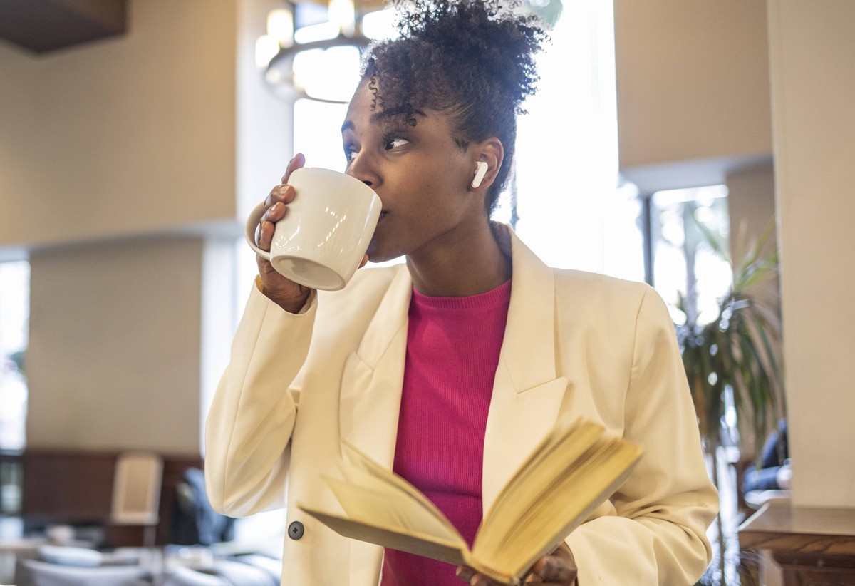 Woman enjoying coffee and reading a book in an urban cafe model released, Symbolfoto, JCCMF13283