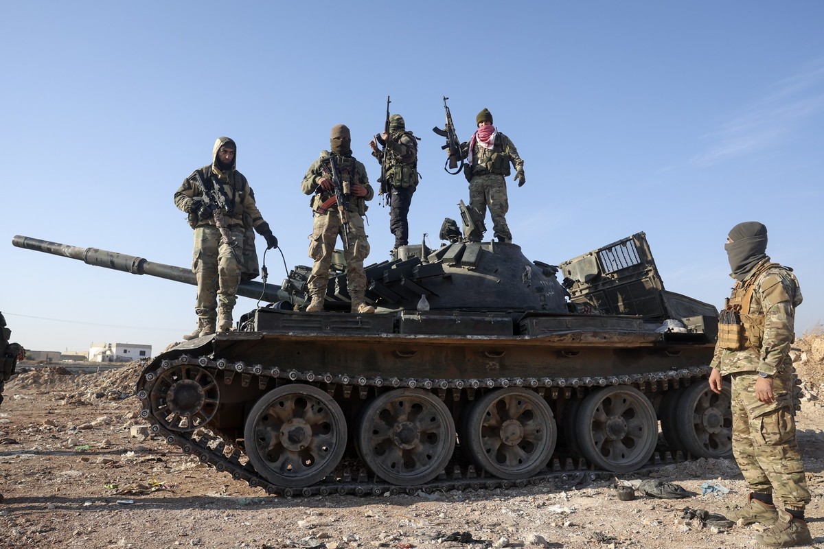 03.12.2024, Syrien, Hama: Syrische Oppositionskämpfer stehen auf einem beschlagnahmten gepanzerten Fahrzeug der syrischen Armee in den Außenbezirken von Hama. Foto: Ghaith Alsayed/AP/dpa +++ dpa-Bildf ...