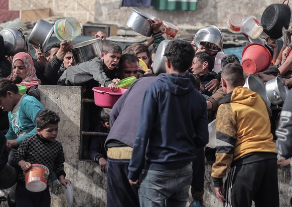 24.12.2023, Pal�stinensische Gebiete, Rafah: Pal�stinenser warten an einer Spendenstelle in einem Fl�chtlingslager im s�dlichen Gazastreifen auf Lebensmittel. Foto: Bashar Taleb/APA Images via ZUMA Pr ...