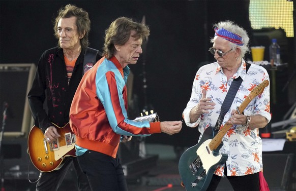 Mick Jagger, center, singer of the band 'The Rolling Stones', hands over a new plectrum to guitarist Keith Richards, right, during the last concert of the 'Sixty' European tour in Berlin, Germany, Wed ...