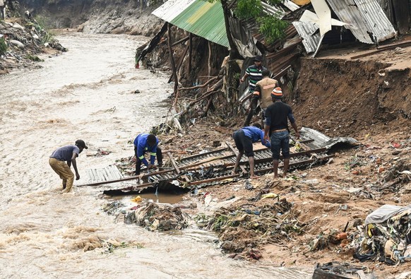 ARCHIV - 15.03.2023, Malawi, Blantyre: Männer bergen Teile ihres zerstörten Hauses nach schweren Regenfällen, die der Zyklon «Freddy» verursacht hat. Im Jahr 2023 ist die Klimakrise in aller Welt zu s ...
