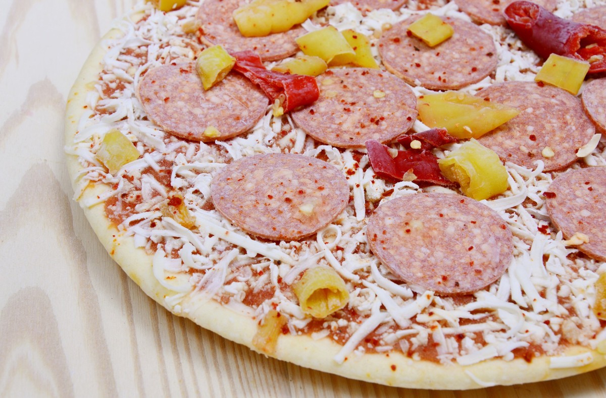 close up from frozen pizza on wooden plate