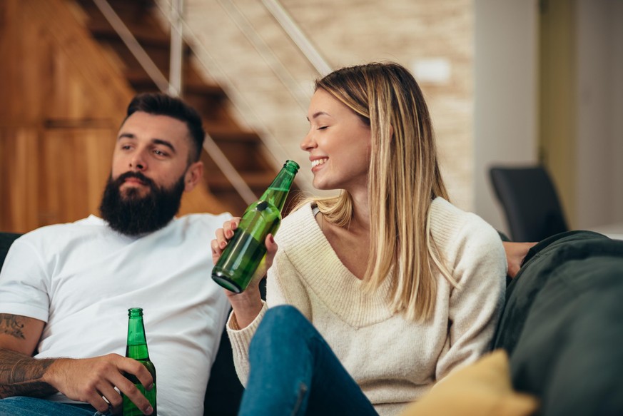 Photo d'un jeune couple buvant de la bière en regardant le match à la maison