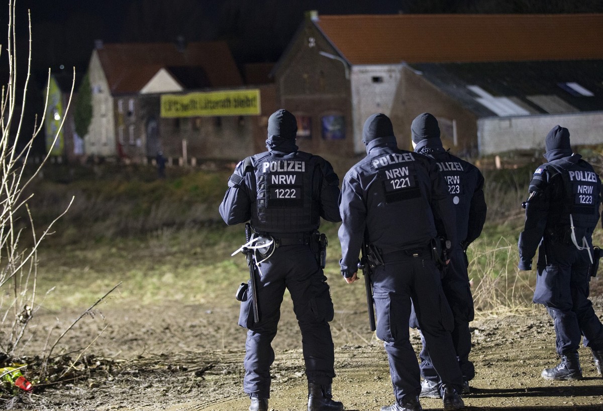 11.01.2023, Nordrhein-Westfalen, Erkelenz: Polizeibeamte stehen nachts vor einem Bauernhof in Lützerath. Der Energiekonzern RWE will die unter Lützerath liegende Kohle abbaggern - dafür soll der Weile ...