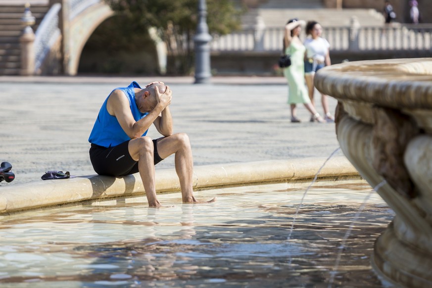 Ein Mann kühlt sich im zentralen Brunnen auf der Plaza de España in Sevilla ab. In 16 der insgesamt 17 Autonomen Gemeinschaften Spaniens sollte am Donnerstag weiterhin Hitzealarm gelten, in fünf diese ...
