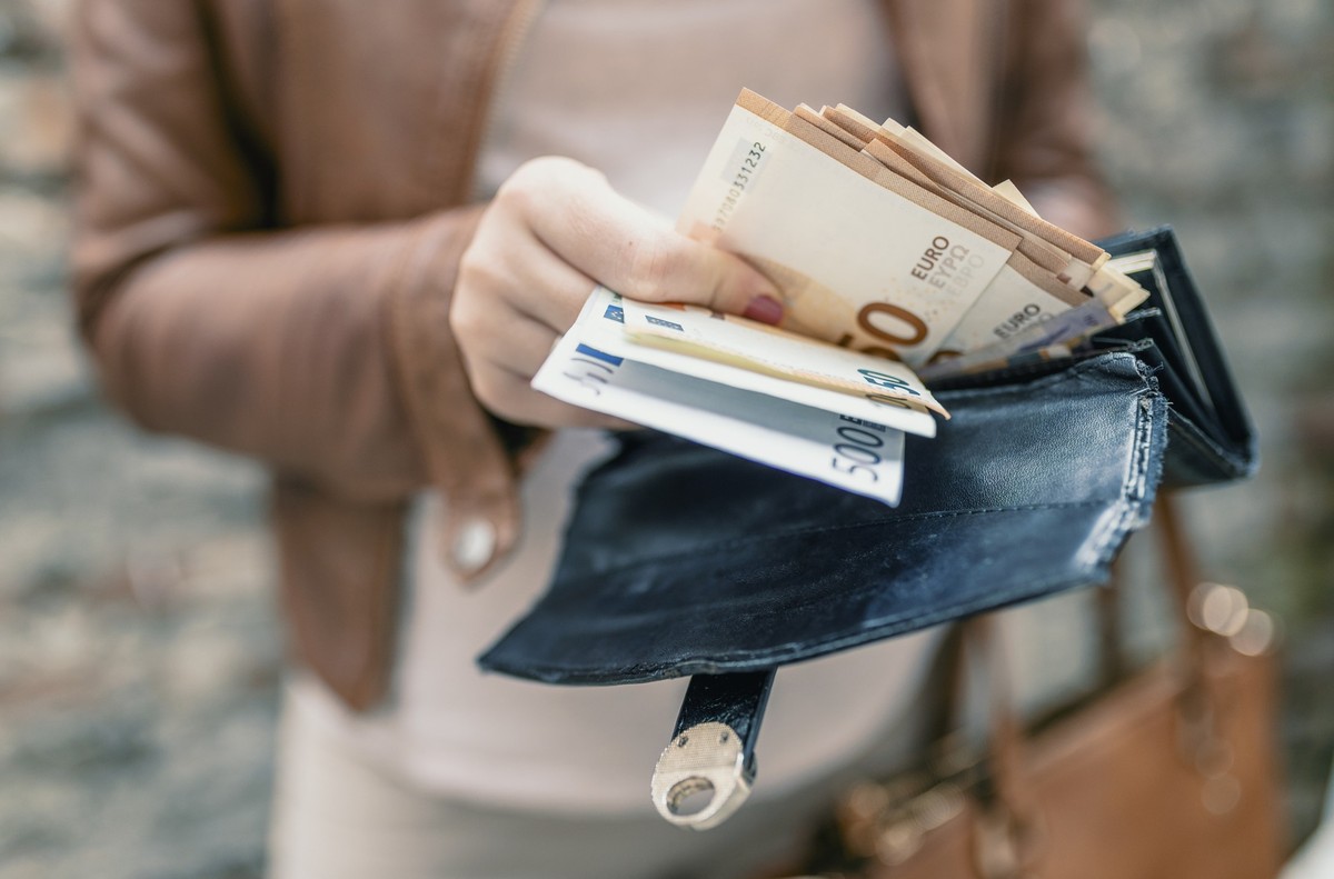 Woman holding in hands wallet with euro money. City girl is taking out money from wallet