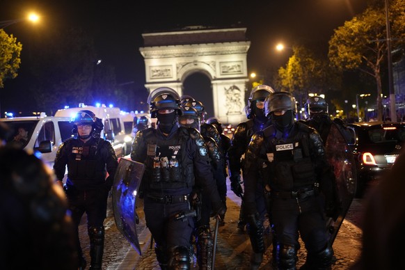 01.07.2023, Frankreich, Paris: Polizisten patrouillieren vor dem Arc de Triomphe auf der Champs Elysees. Aufgrund der anhaltenden Unruhen in Frankreich sollen in der Nacht zum Sonntag erneut 45 000 Po ...