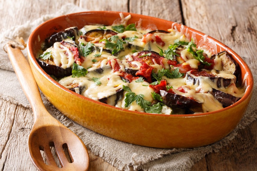 healthy meal of baked eggplants with tomatoes, herbs and cheese close-up in a baking dish on a table. horizontal