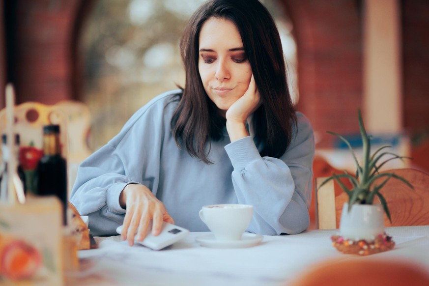 Girl finding her mobile disturbing and annoying while enjoying her coffee