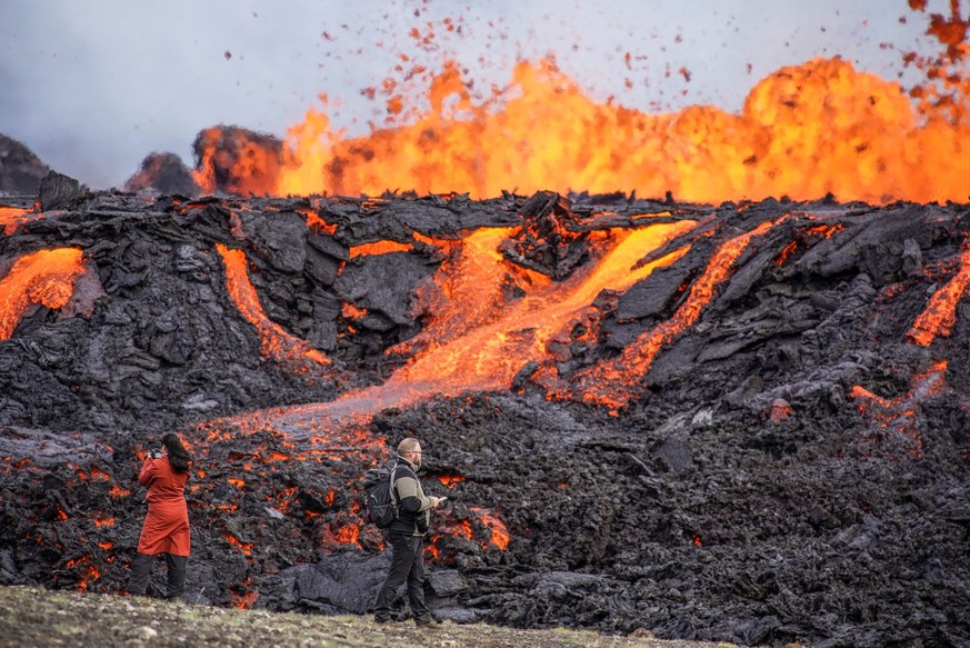 Menschen betrachten Lava, die auf dem Vulkan Fagradalsfjall fließt. Auf Island hat ein erneuter Vulkanausbruch begonnen. Die erwartete Eruption habe in der Nähe des Bergs Fagradalsfjall auf der Reykja ...