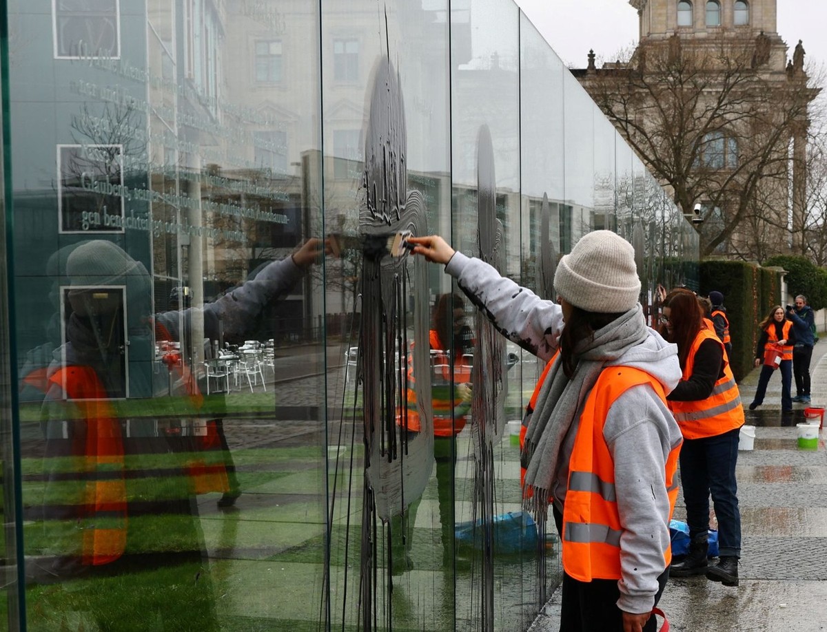 Activists of "Letzte Generation" (Last Generation) cover the "Basic Law 49" constitutional rights artwork with black liquid for postering, at a Bundestag building, during a protest ...