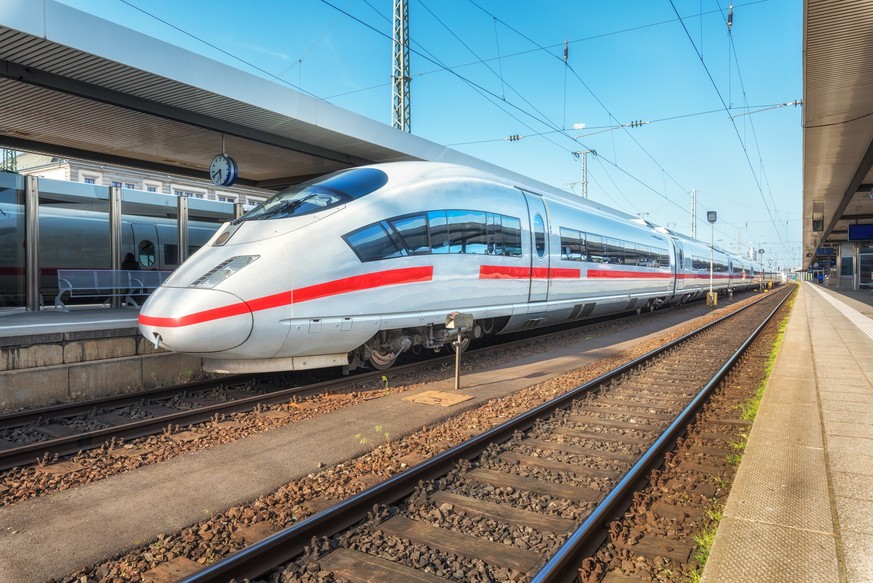 High speed white train on the railway station at sunset. Nuremberg, Germany. Modern intercity train on the railway platform. Industrial. Amazing passenger train on railroad. Transportation. Europe