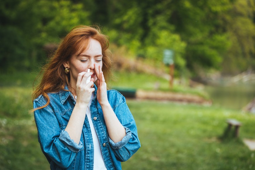 Woman is having flu and she is using nasal spray to help herself. Woman using nasal spray. Nasal spray to help a cold. Sick with a rhinitis woman dripping nose. Woman applies nasal spray