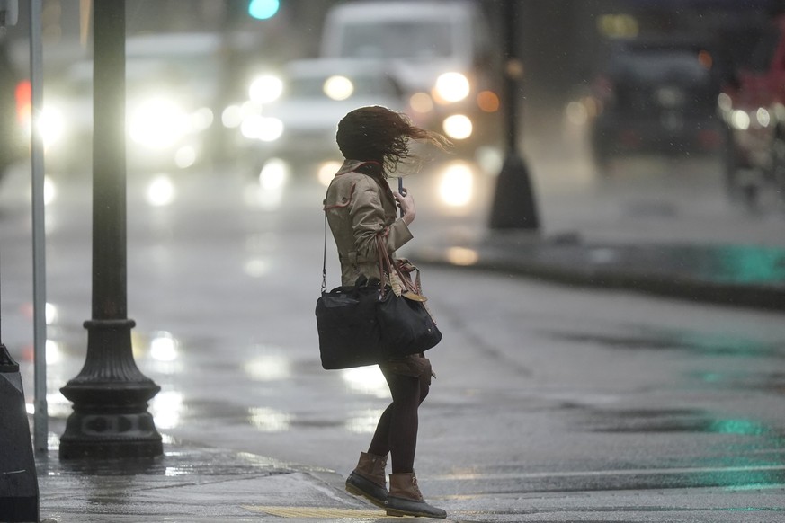 A pedestrian is buffeted by wind and rain while crossing a street, Monday, Dec. 18, 2023, in Boston. A storm moving up the East Coast brought heavy rain and high winds to the Northeast on Monday, thre ...