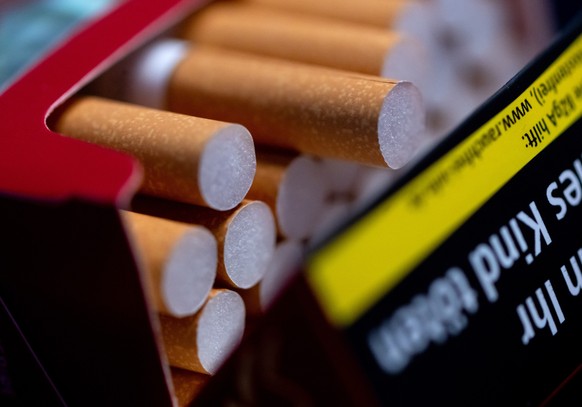 ILLUSTRATION - 06.03.2023, Bayern, M�nchen: Eine ge�ffnete Zigarettenpackung liegt auf einem Tisch. Am 9.3. wird das EuGH-Urteil zu Warnhinweisen beim Verkauf von Zigaretten am Automaten erwartet. Hin ...