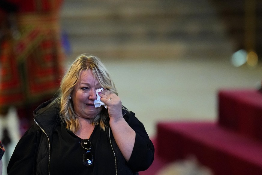 A woman cries after paying her respects by the coffin of Queen Elizabeth II as it Lies in State inside Westminster Hall, at the Palace of Westminster in London, England, Saturday, Sept. 17, 2022. (AP  ...