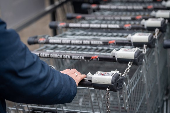 Bavaria, Germany - November 26, 2023: A man takes a shopping cart from a shopping cart box to go shopping *** Ein Mann nimmt einen Einkaufswagen aus einer Einkaufswagenbox zum Einkaufen