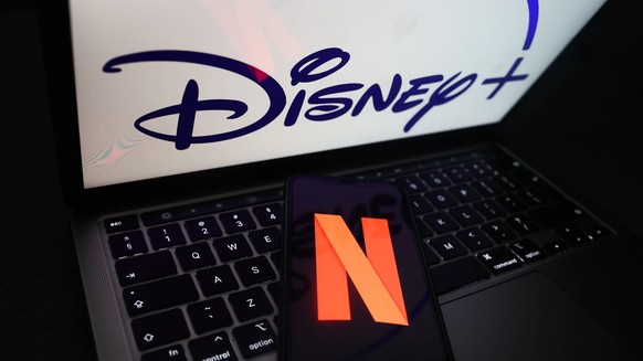 Popular Streaming Services Photo Illustrations Netflix icon displayed on a phone screen and Disney logo displayed on a laptop screen are seen in this illustration photo taken in Krakow, Poland on Nove ...