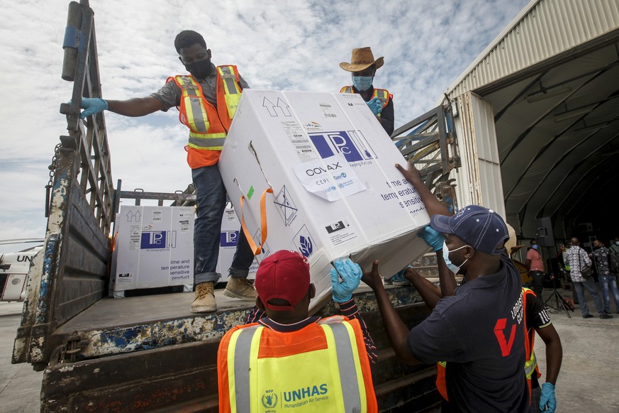 15.03.2021, Somalia, Mogadischu: Mitarbeiter laden eine Kiste mit dem Corona-Impfstoff AstraZeneca von einem LKW am Flughafen von Mogadischu. Es handelt sich hierbei um die erste Lieferung von insgesa ...
