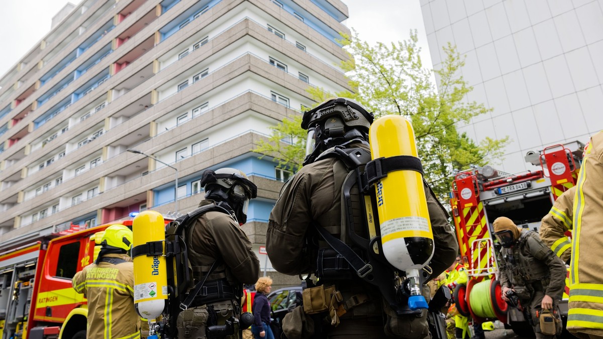 ARCHIV - 11.05.2023, Nordrhein-Westfalen, Ratingen: Polizeibeamte mit Gasmasken und Feuerwehrleute stehen vor einem Hochhaus in Ratingen. Im Prozess um den verheerenden Feuer-Angriff auf Einsatzkr�fte ...