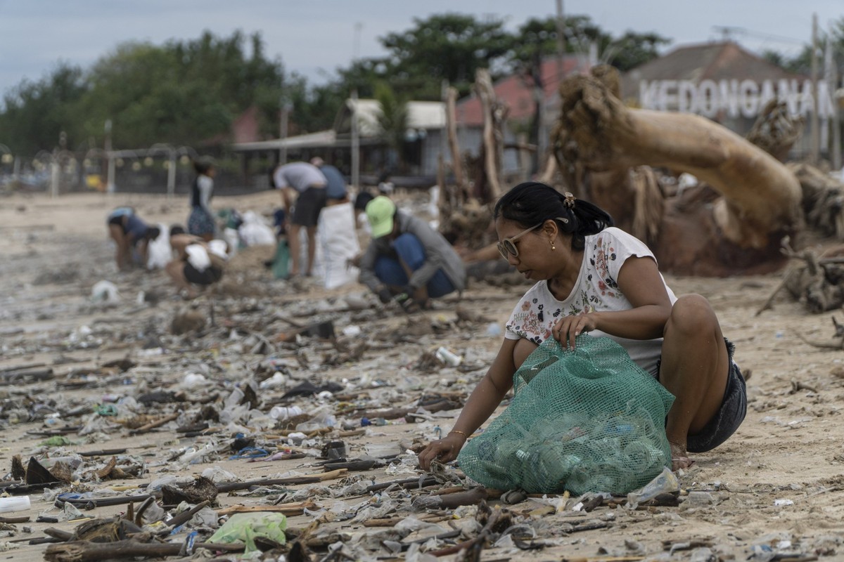 A volunteer picks up trash washed ashore by seasonal monsoon tides at Kedonganan Beach in Badung on the resort island of Bali, Indonesia, Sunday, Jan. 5, 2025. (AP Photo/Dicky Bisinglasi)