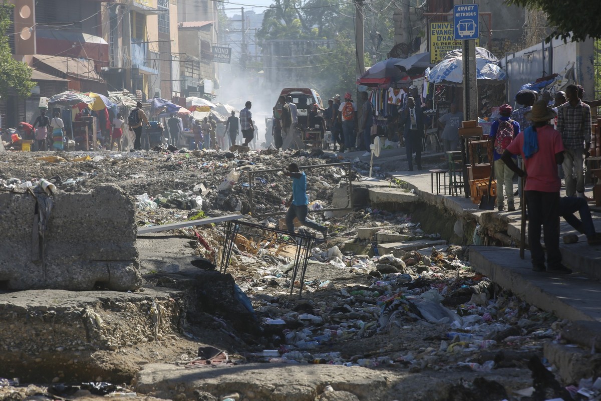 ARCHIV - 02.12.2024, Haiti, Port-au-Prince: Ein Mann überquert eine durch Regenfälle zerstörte Straße in Port-au-Prince, Haiti. (zu dpa: «Bericht: Mehr als 100 Tote bei Massaker in Haiti») Foto: Odely ...