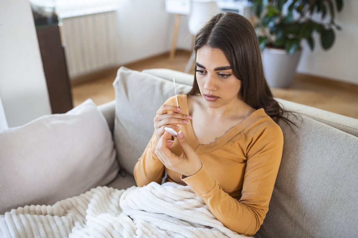 woman using cotton swab while doing coronavirus PCR test at home. Woman using coronavirus rapid diagnostic test. Young woman at home using a nasal swab for COVID-19.