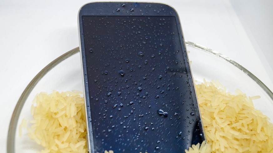 Handy, das ins Klo gefallen ist, wird in einer Schuessel mit Reis getrocknet Mobile fell in toilet bowl and is dried in a bowl with rice BLWS699830 *** Cell phone, the ins Toilet please is, will in a  ...