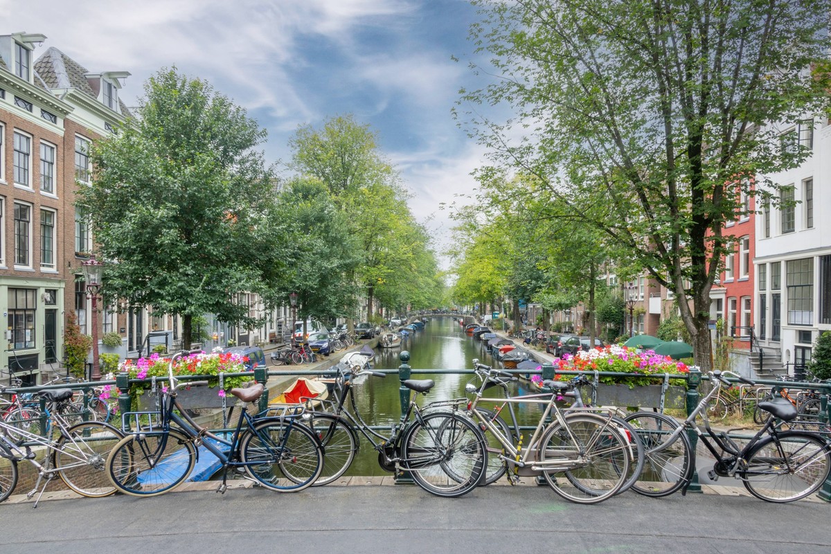 Bicycles on the Summer Amsterdam Bridge Netherlands. Summer day in Amsterdam. High clouds in the blue sky. Several bicycles are parked near the railing of a bridge over a canal Copyright: xZoonar.com/ ...