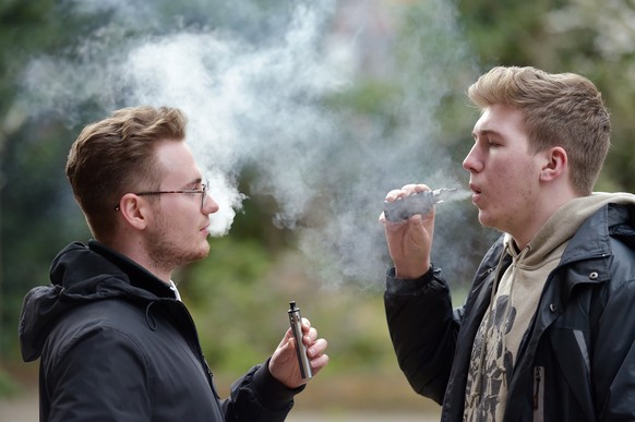 ARCHIV - 21.02.2020, Gro�britannien, London: Zwei junge Menschen rauchen eine E-Zigarette. Seit Jahren sinkt die Zahl der Raucher in Gro�britannien. 2022 waren es noch 12,9 Prozent der Erwachsenen. Do ...