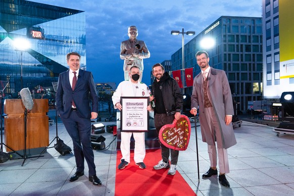 HANDOUT - 21.04.2021, Berlin: J�rgen Krogmann (l), Oberb�rgermeister von Oldenburg, Entertainer Klaas Heufer-Umlauf (2.v.r) und Joko Winterscheidt (r) stehen vor einer �berlebensgro�en Statue, die Kla ...