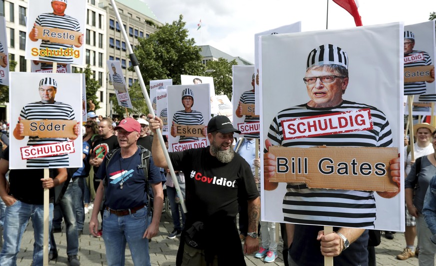 People attend a protest rally in Berlin, Germany, Saturday, Aug. 29, 2020 against new coronavirus restrictions in Germany, holding a sign with Bill Gates in prison clothes, reading &quot;Guilty&quot;. ...