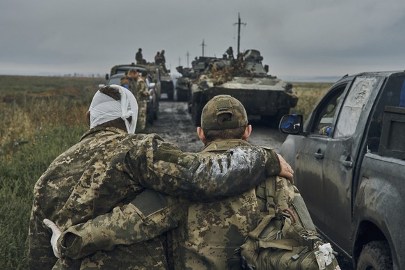 12.09.2022, Ukraine, ---: Ein ukrainischer Soldat hilft einem verwundeten Kameraden auf der Stra�e in dem befreiten Gebiet in der Region Charkiw. Die ukrainischen Truppen haben am 12.09.2022 weite Tei ...