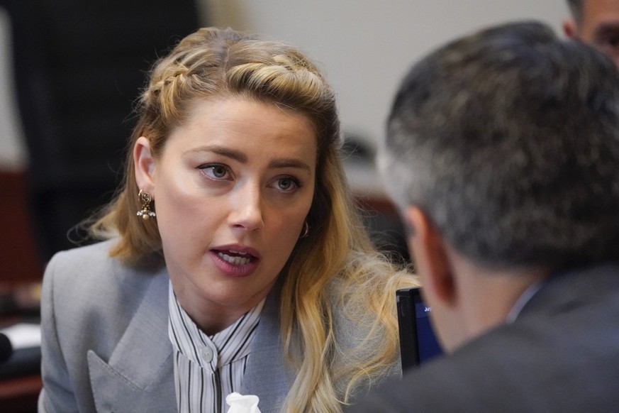 Actor Amber Heard speaks to her legal team in the courtroom at the Fairfax County Circuit Courthouse in Fairfax, Va., Friday, May 27, 2022. Actor Johnny Depp sued his ex-wife Amber Heard for libel in  ...