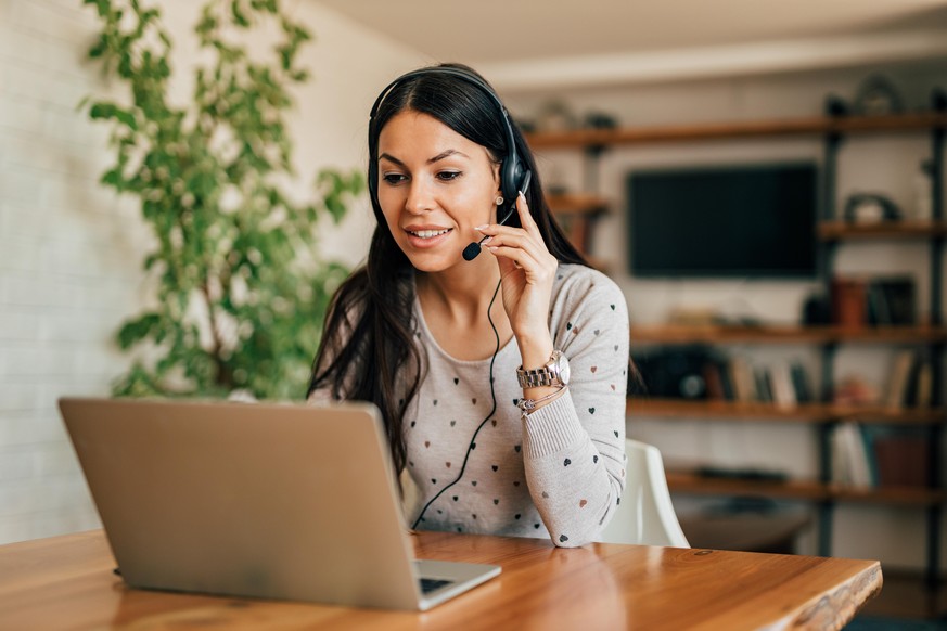 Portrait of a cute woman with headset and laptop at home office.