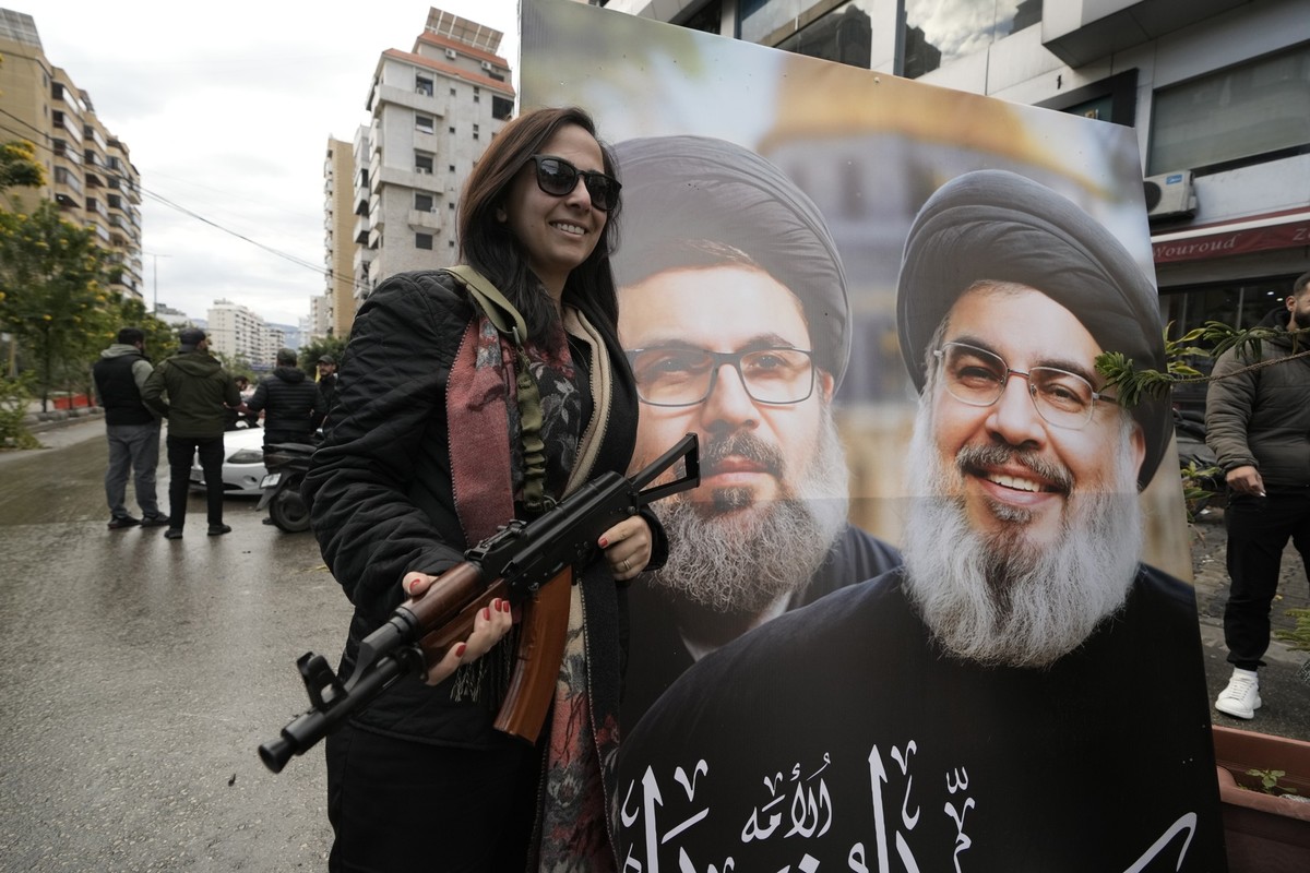 A woman poses in front of a picture of slain Hezbollah leader Hassan Nasrallah, right, and slain Hezbollah official Hashem Safieddine, as she returns to Dahiyeh, in Beirut, Lebanon, following a ceasef ...