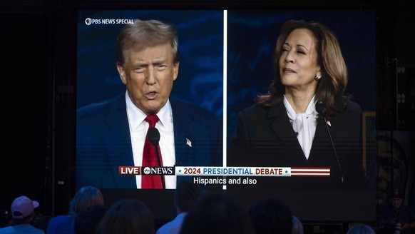 10. September 2024, Philadelphia, Pennsylvania, USA: Der ehemalige Präsident DONALD TRUMP und die Vizepräsidentin KAMALA HARRIS sind auf einem Monitor zu sehen, während die Gäste der Präsidentendebütfeier der Harris-Walz-Kampagne zuschauen ...