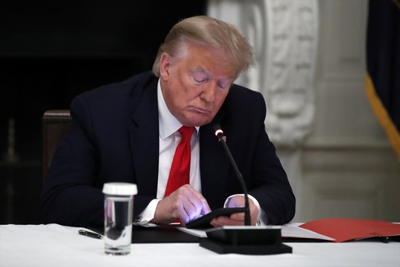 FILE - In this Thursday, June 18, 2020 file photo, President Donald Trump looks at his phone during a roundtable with governors on the reopening of America&#039;s small businesses, in the State Dining ...