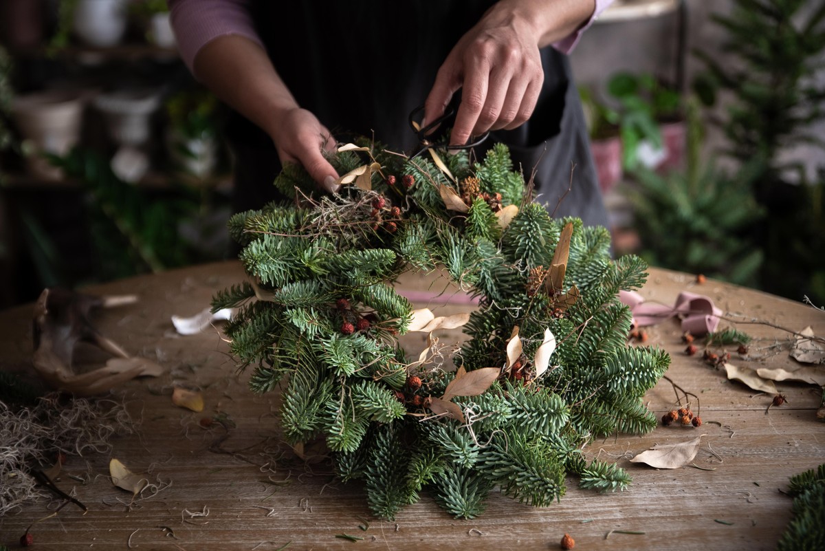 Woman making Christmas wreath of spruce, step by step. Concept of florist's work before the Christmas holidays.