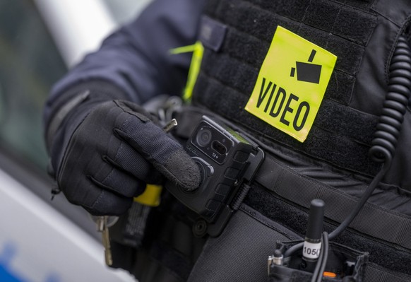 ARCHIV - 05.12.2022, Berlin: Ein Polizist schaltet die Bodycam auf seiner Uniform ein, aufgenommen bei einem Pressetermin zur Ausweitung des Einsatzes von Bodycams bei Berliner Polizei und Feuerwehr.  ...