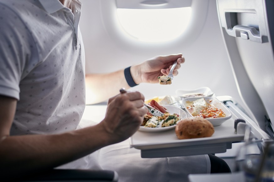 Passenger eating airline meal. Menu in business class on medium haul flight.