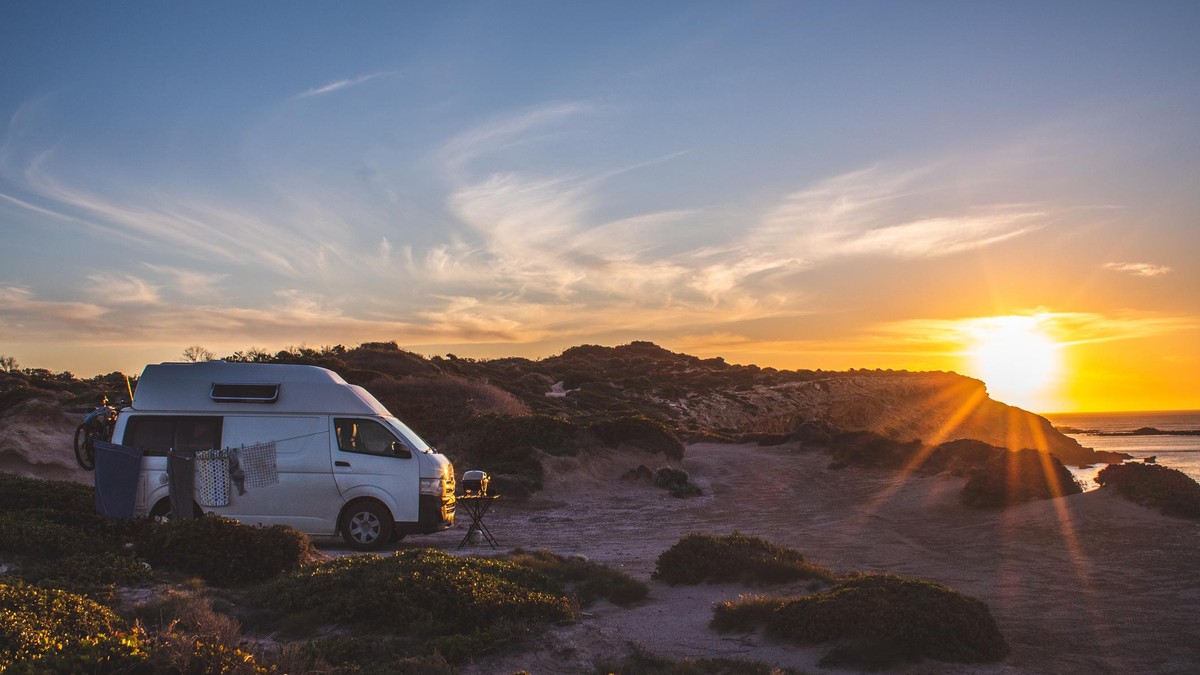 Camping on a cliff edge in a camper van, beautiful sunset landscape