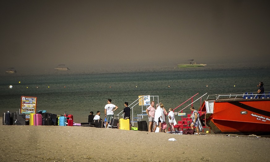 22.07.2023, Griechenland, Rhodos: Touristen stehen an einem Strand, wohin sie wegen eines Waldbrandes auf der griechischen Insel Rhodos in Sicherheit gebracht worden sind. Ein großer Brand auf der gri ...