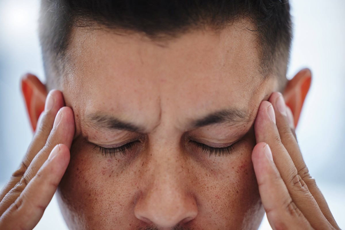 Man, closeup and headache with fatigue, burnout and stress in office for business deadline. Frustrated, person and migraine with brain fog in workplace and health crisis from anxiety or worry. ,model ...