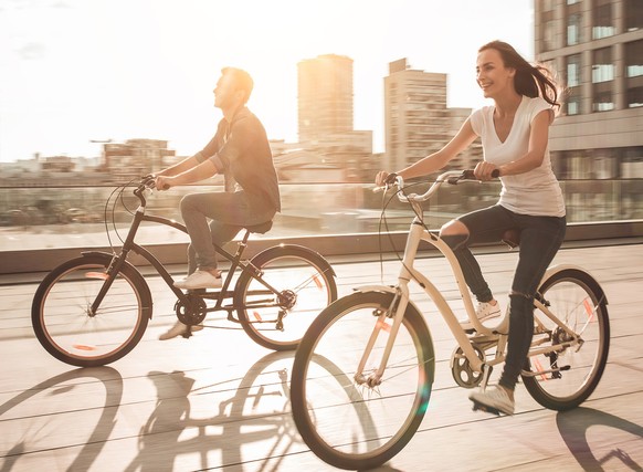 Young romantic couple is cycling in the city on the sunset