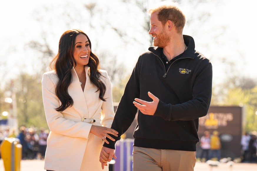 ARCHIV - 17.04.2022, Niederlande, Den Haag: Prinz Harry (r), Herzog von Sussex, und Meghan, Herzogin von Sussex, nehmen an den Leichtathletikwettbewerben der Invictus Games 2022 im Zuiderpark teil. Am ...