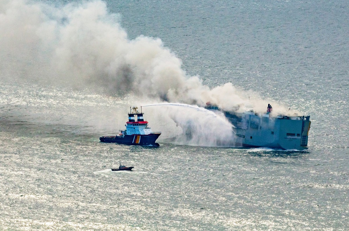 26.07.2023, Niederlande, Ameland: Eine Luftaufnahme zeigt den deutschen Notschlepper &quot;Nordic&quot; (l), der das Feuer auf einem brennenden Frachter in der Nordsee bekämpft. Wie die niederländisch ...