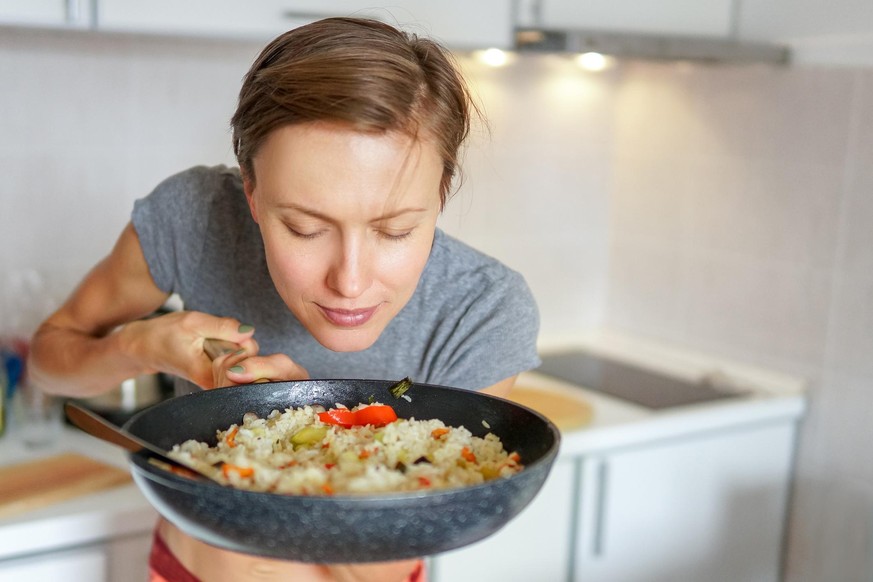 oung woman going to eat rice with vegetables, smelling delicious aroma fro just prepared food