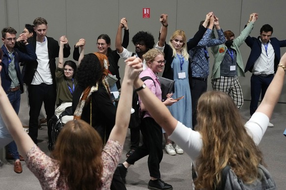 Demonstrators raise their hands, many wearing &quot;end fossil fuels&quot; stickers, as negotiators head to a new session of talks at the COP28 U.N. Climate Summit, Monday, Dec. 11, 2023, in Dubai, Un ...